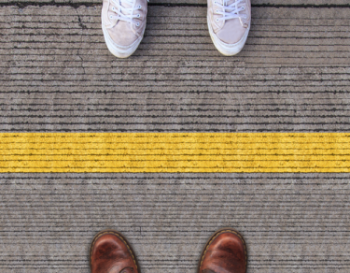 Two feet standing on each side of a yellow line