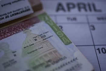 H1B visa page on passport sitting on a calendar denied because of unlawful policies.