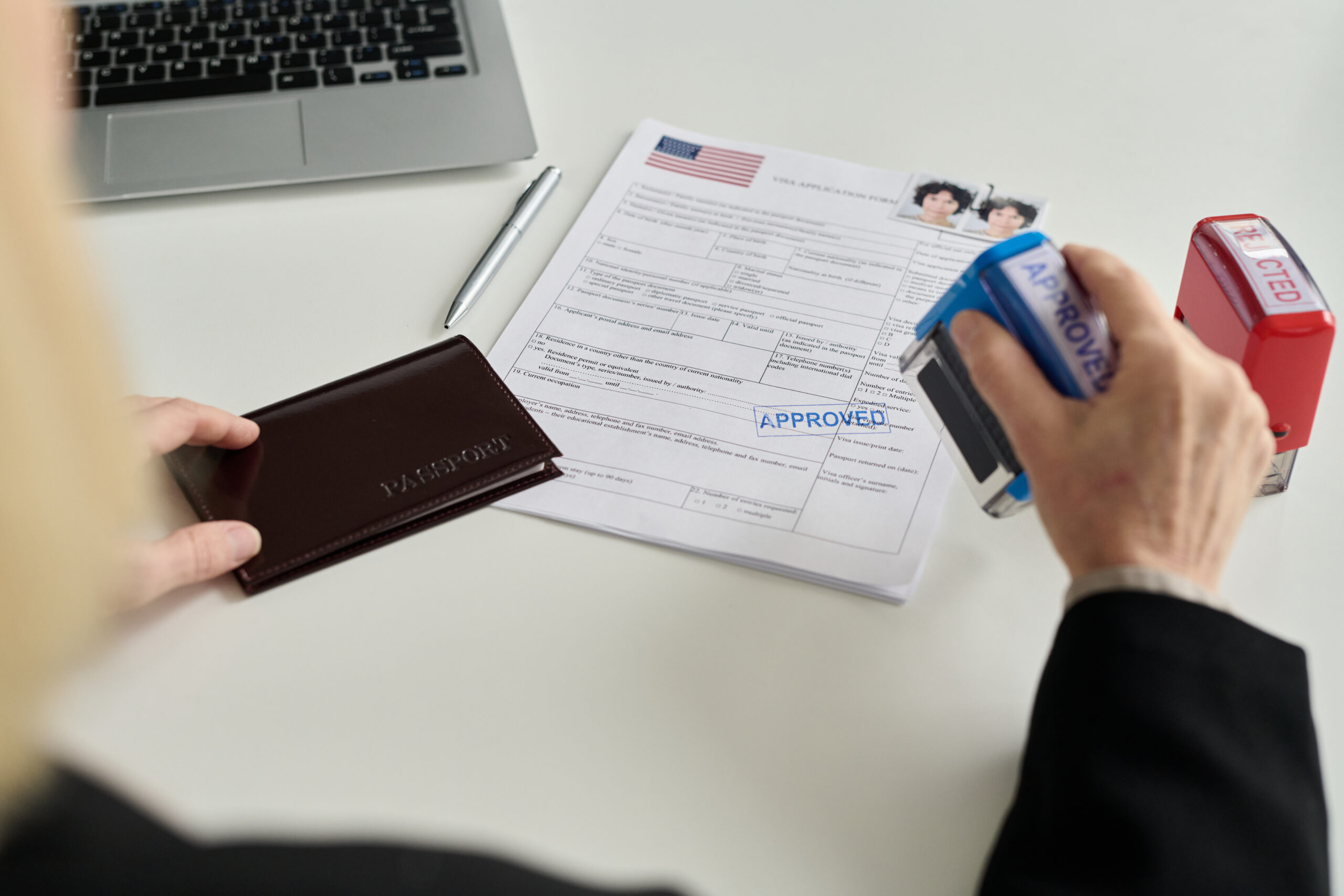 Close up of immigration office worker approving visa application. Adjustment of Status vs. Consular Processing