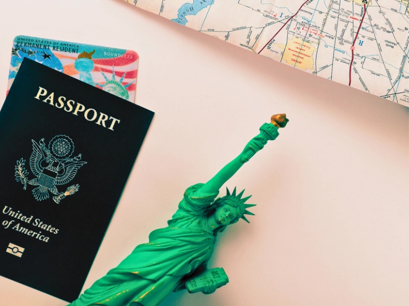 United States passport, a permanent resident card, a map and Statue of Liberty flat lay on the gradient surface. work in the U.S. while my green card application is pending