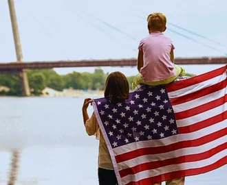 Family wrapped in American flag looking at bridge. Family-Based Green Card Process