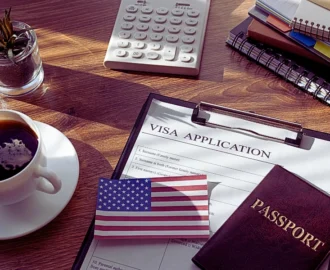 a visa application form on a clipboard, accompanied by a small American flag card and a passport. H-1B and L-1 Visas