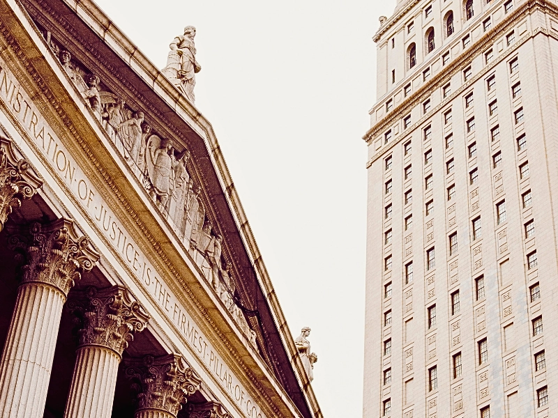 a classical building with large columns and an inscription that reads, "ADMINISTRATION OF JUSTICE IS THE FIRMEST PILLAR OF GOOD GOVERNMENT," indicating a judicial or governmental purpose. Writ of Mandamus for Immigration Delays