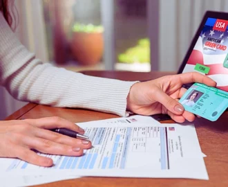 Person holding American Green Card over application forms. travel while your green card renewal is pending