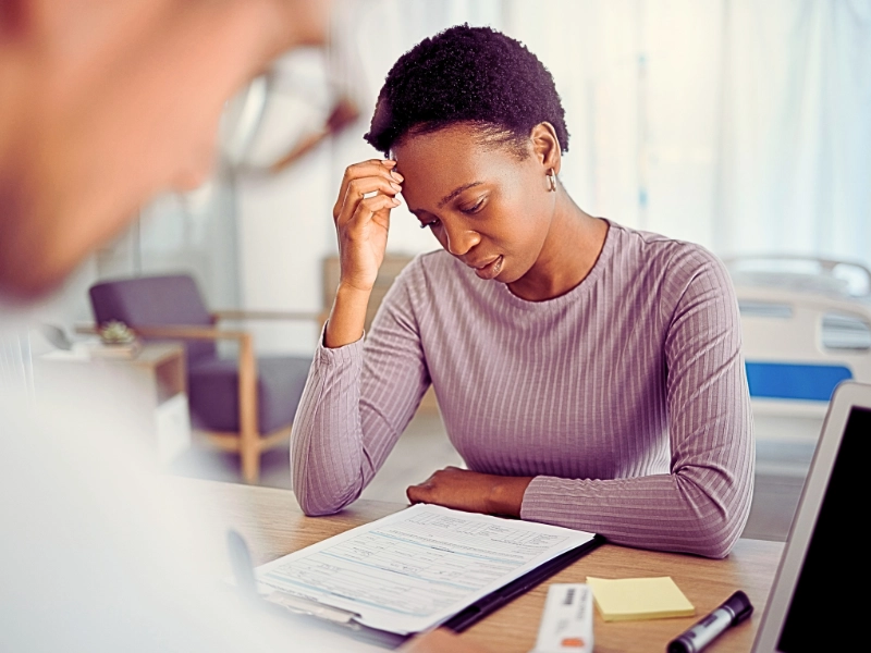Concerned woman looking at paperwork in medical office. Immigration medical exam is delayed
