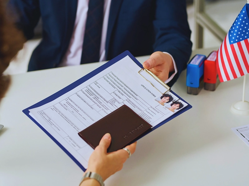 A person handing over an application form and passport. Asylum Work Permit Changes